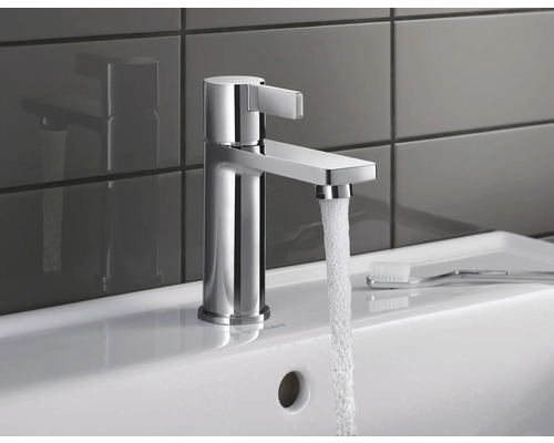 Wasserhahn aus Chrom auf einem Waschbecken mit fließendem Wasser.