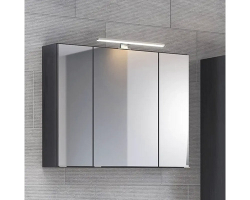 Armoire de toilette à trois portes avec éclairage LED supérieur et corps foncé sur un mur gris.