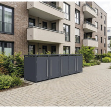 Mülltonnenbox aus Metall vor einem Wohnhaus