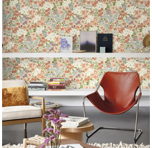 Salon avec papier peint à motifs floraux, étagères, fauteuils et décorations pour une ambiance chaleureuse