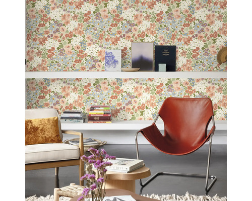 Salon avec papier peint à motifs floraux, étagères, fauteuils et décorations pour une ambiance chaleureuse