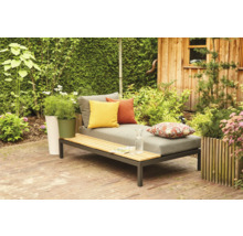 Gartenszene mit Liege, Kissen, Pflanzen und Holzhütte