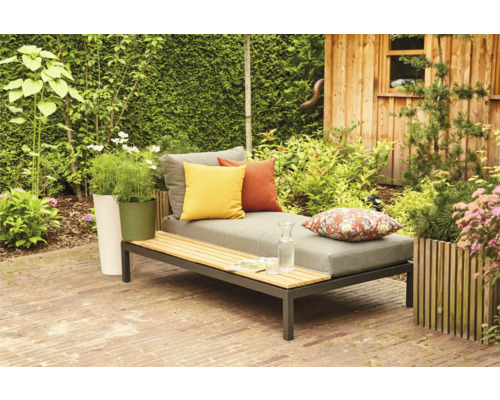 Gartenszene mit Liege, Kissen, Pflanzen und Holzhütte
