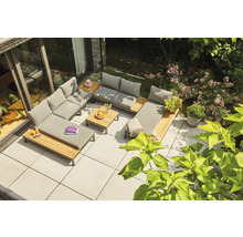 Loungegruppe aus Holz und grauem Polster auf einer Terrasse, kombiniert mit einem Holztisch und grüner Vegetation.