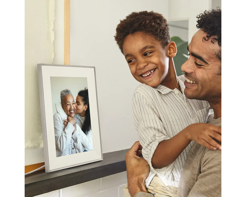 Cadre photo numérique sur une étagère, regardé par un père et son fils souriants.