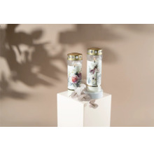 Deux bougies funéraires à motif floral sur un socle blanc