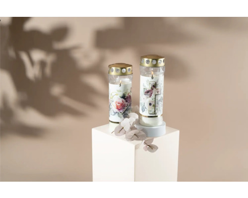 Zwei Grablichter mit Blumenmotiven auf einem weißen Sockel.