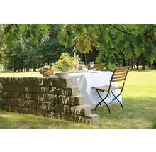 Table de jardin dressée avec mur et chaise pliante sur une pelouse