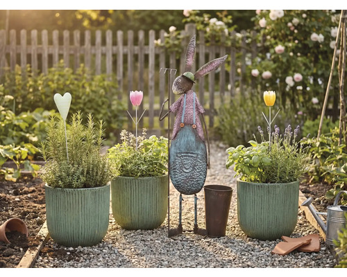 Scène de jardin avec pots plantés, lièvre en métal et décorations sur un chemin de gravier