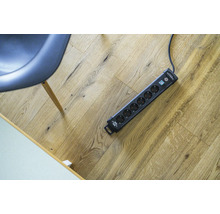 Mehrfachsteckdose auf einem Holzboden neben einem Stuhl.