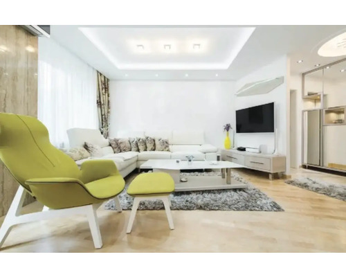 Salon moderne lumineux avec canapé d'angle blanc, fauteuil vert citron avec repose-pieds, tapis gris, table basse et parquet en bois clair.