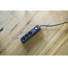 Steckdosenleiste mit drei Steckplätzen und Überspannungsschutz auf Holzboden