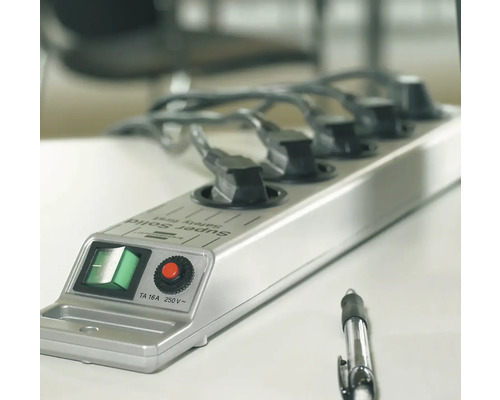 Mehrfachsteckdose mit fünf Steckplätzen und angeschlossenen Stromkabeln auf einem Tisch