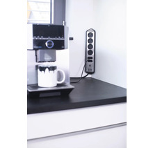 Bloc multiprise avec cinq prises et deux ports USB à côté d'une machine à café sur un plan de travail