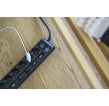 Multiprise avec interrupteur et câble USB branché sur un plancher en bois