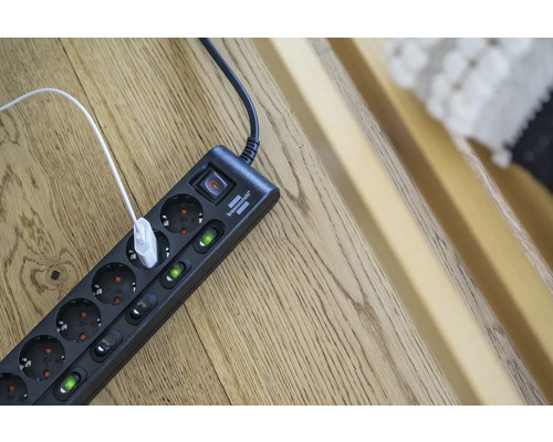 Multiprise avec interrupteur et câble USB branché sur un plancher en bois