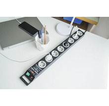 Mehrfachsteckdose mit Überspannungsschutz auf einem Schreibtisch mit Laptop und Telefon