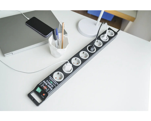 Mehrfachsteckdose mit Überspannungsschutz auf einem Schreibtisch mit Laptop und Telefon