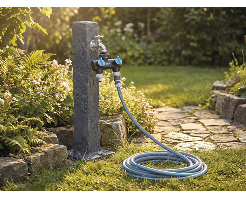 Gartenszene mit Wasserhahn, Verteiler und Gartenschlauch auf einem Rasen