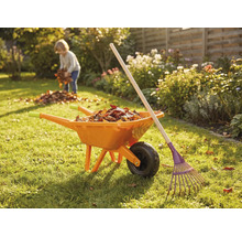 Gartenszene mit Schubkarre, Rechen und Kind beim Laubsammeln