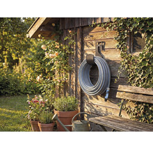 Scène de jardin avec enrouleur de tuyau sur mur en bois, entouré de plantes