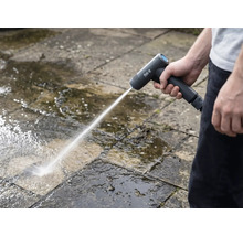 Une personne nettoie des dalles de pierre à l'extérieur avec un nettoyeur haute pression sans fil.
