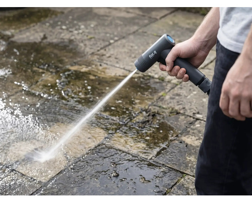 Une personne nettoie des dalles de pierre à l'extérieur avec un nettoyeur haute pression sans fil.