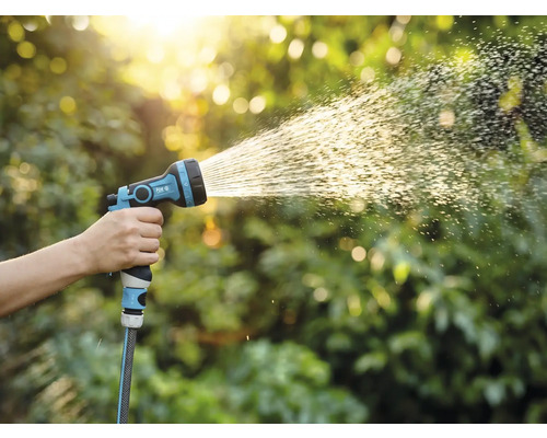 Eine Hand hält eine Gartenspritze, aus der Wasser austritt.