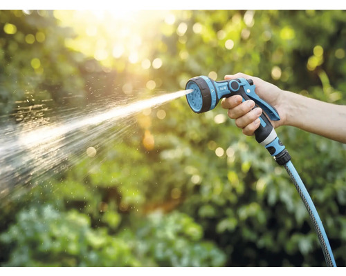 Eine Hand hält eine Gartenspritze, aus der Wasser spritzt