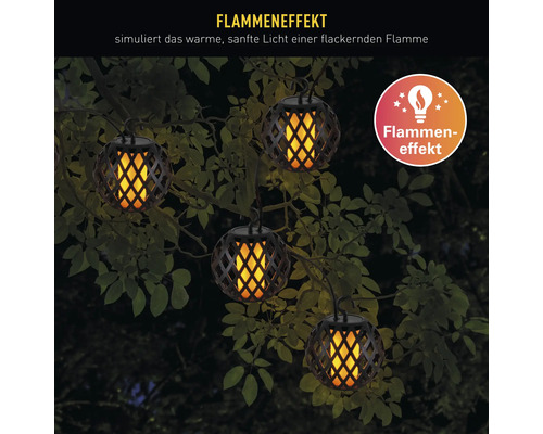 Plusieurs lampes de jardin suspendues avec effet de flamme entre les branches