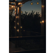 Scène avec une guirlande lumineuse dotée de lampes sphériques, fixée sur une structure en bois, créant une ambiance chaleureuse.