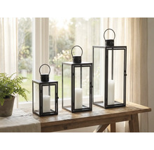 Drei dekorative Windlichter aus Metall und Glas mit Kerzen auf einem Tisch.