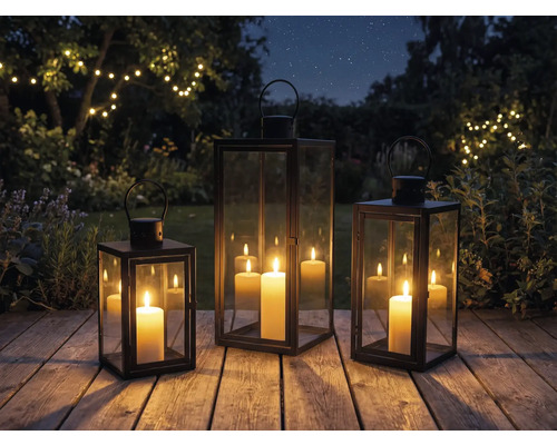 Drei Laternen mit Kerzen auf einer Holzterrasse im Garten