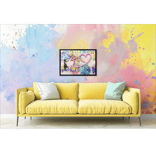 Canapé jaune avec coussins devant un mur avec une image encadrée d'une fille et d'un cœur