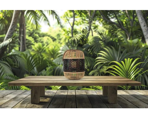 Lanterne décorative en bambou sur une table en bois devant une jungle en arrière-plan