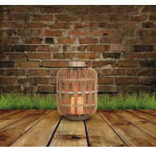 Dekorative Laterne aus Bambus mit Kerzen auf Holzboden vor Backsteinmauer