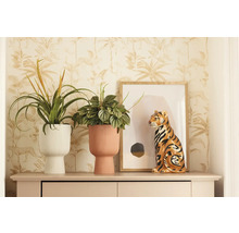 Scène décorative avec deux plantes d'intérieur dans des pots de fleurs structurés et une figurine de tigre sur un buffet devant un papier peint à motifs