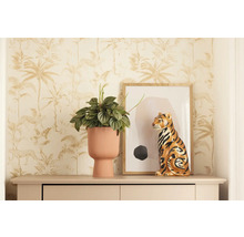 Scène décorative avec plante d'intérieur dans un pot côtelé, figurine de tigre et œuvre d'art encadrée sur une commode devant un papier peint jungle.