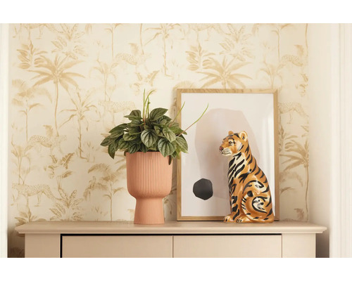 Scène décorative avec plante d'intérieur dans un pot côtelé, figurine de tigre et œuvre d'art encadrée sur une commode devant un papier peint jungle.
