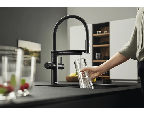 Schwarze Küchenarmatur mit schwenkbarem Auslauf und Person, die ein Glas mit Wasser befüllt