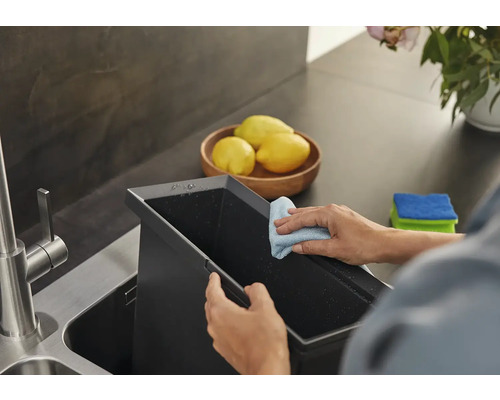 Une personne nettoie un évier de cuisine avec un chiffon