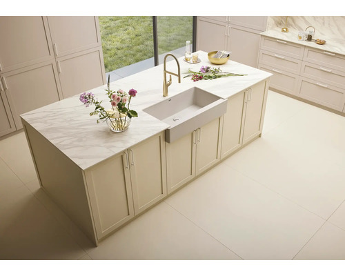 Îlot de cuisine avec évier, robinetterie et plateau en marbre dans une pièce lumineuse