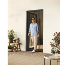 Femme franchissant une porte avec moustiquaire donnant sur une terrasse avec des plantes