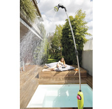 Scène de jardin avec douche extérieure, terrasse en bois et personne se relaxant