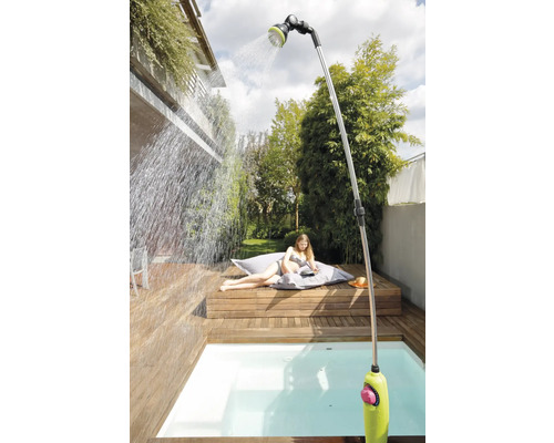 Scène de jardin avec douche extérieure, terrasse en bois et personne se relaxant