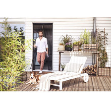 Extérieur avec homme, chien, porte moustiquaire, plantes et chaise longue sur une terrasse en bois