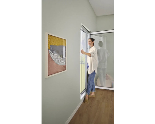 Femme ouvrant une porte anti-insectes dans une pièce lumineuse.