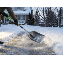 Personne déneigeant un trottoir avec une pelle à neige
