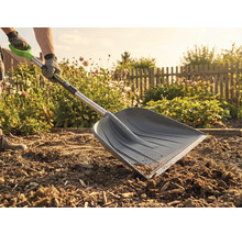 Un jardinier utilise une pelle à neige dans le jardin pour des travaux de terrassement.