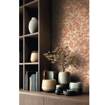 Vliestapete mat Kiferemuster an Rostoptik hannert engem donkelen Holzregal mat Keramikvasen a Bicher.